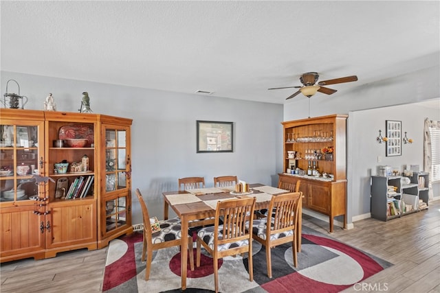 dining area featuring a textured ceiling, ceiling fan, and light hardwood / wood-style flooring