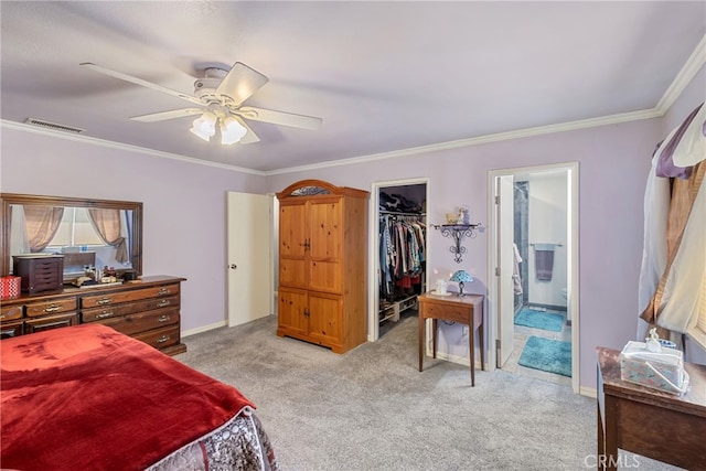 carpeted bedroom with a closet, ensuite bath, a walk in closet, ornamental molding, and ceiling fan