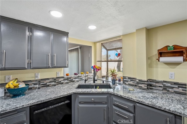 kitchen featuring gray cabinetry, black dishwasher, light stone counters, and sink