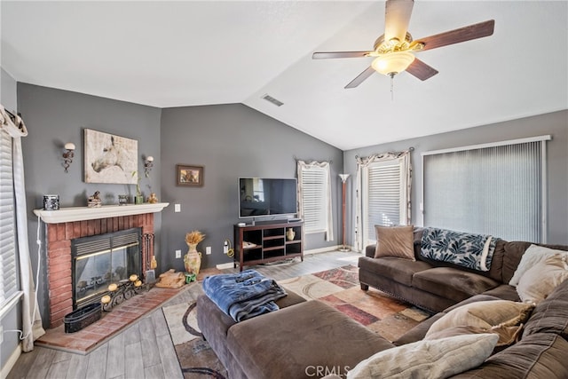 living room with lofted ceiling, ceiling fan, light hardwood / wood-style flooring, and a brick fireplace