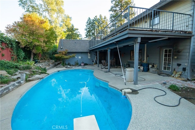 view of swimming pool featuring a diving board and a patio area