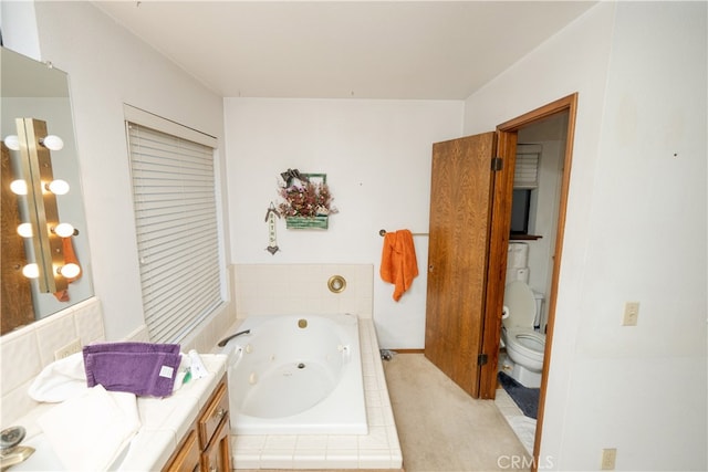 bathroom featuring tiled tub, vanity, and toilet