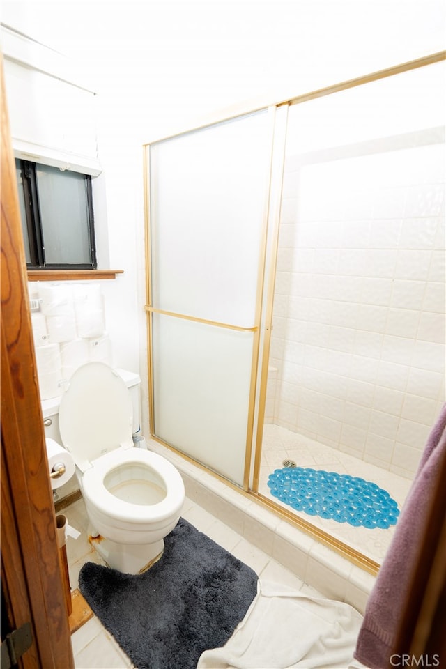 bathroom featuring tile patterned flooring, a shower with shower door, and toilet