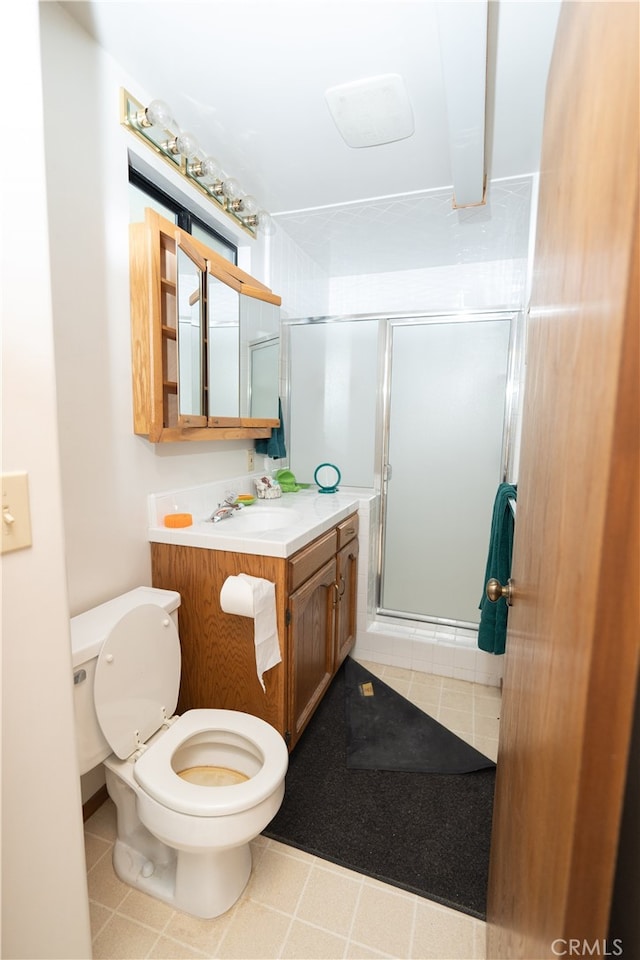 bathroom with tile patterned floors, a shower with shower door, vanity, and toilet