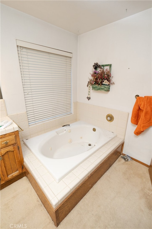 bathroom featuring tiled tub and vanity