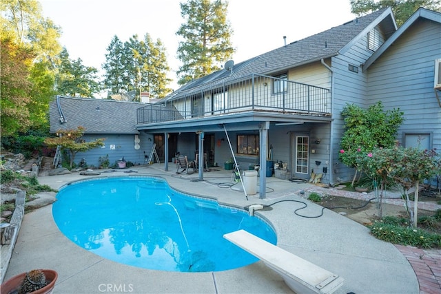 view of pool with a diving board and a patio