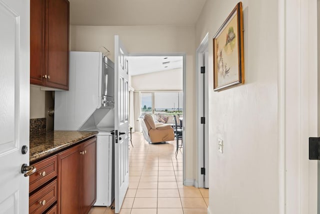 kitchen featuring lofted ceiling, light tile patterned flooring, and dark stone countertops