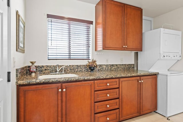 interior space featuring stacked washer / dryer, sink, light tile patterned floors, and cabinets