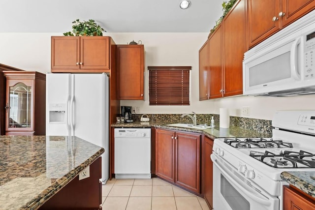 kitchen with light tile patterned flooring, sink, dark stone counters, and white appliances