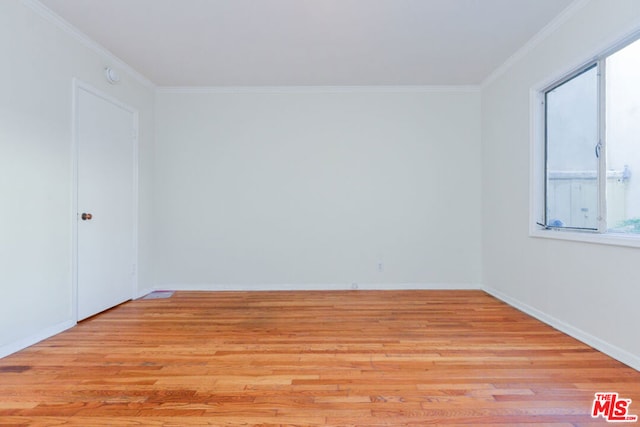 empty room featuring crown molding and light hardwood / wood-style flooring