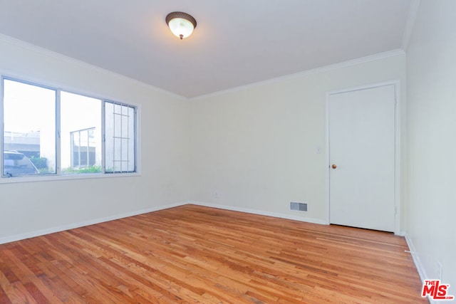 empty room with crown molding and light hardwood / wood-style flooring