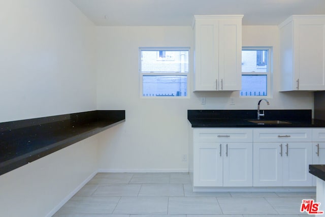 kitchen with white cabinets, light tile patterned flooring, and sink