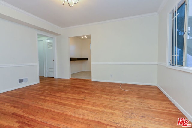 empty room featuring light wood-type flooring and ornamental molding