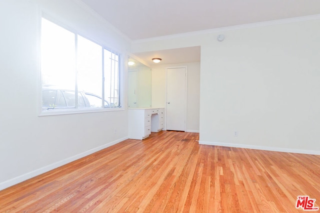 spare room featuring light wood-type flooring and crown molding