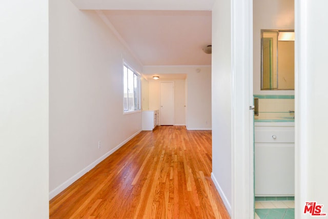 hallway with light hardwood / wood-style floors and ornamental molding