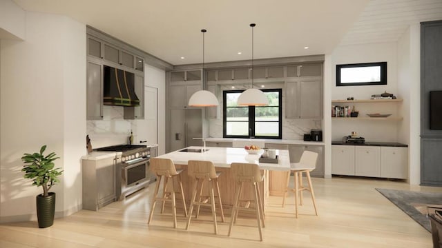 kitchen with appliances with stainless steel finishes, exhaust hood, backsplash, a kitchen island with sink, and gray cabinetry