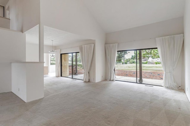 empty room with light colored carpet and high vaulted ceiling