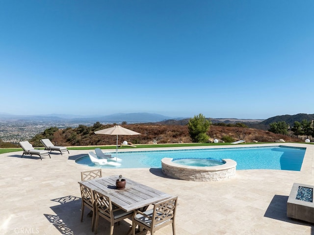 view of pool featuring a patio, a mountain view, and an in ground hot tub