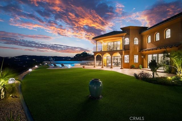 yard at dusk with a patio and a balcony