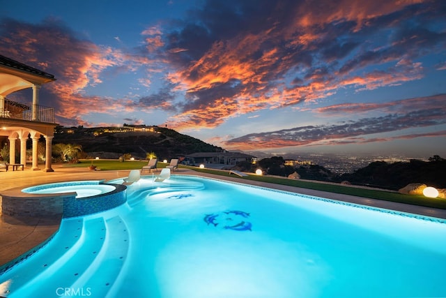 pool at dusk with an in ground hot tub