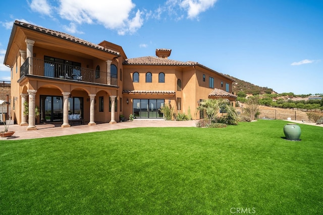 back of property featuring a balcony, a patio, and a yard