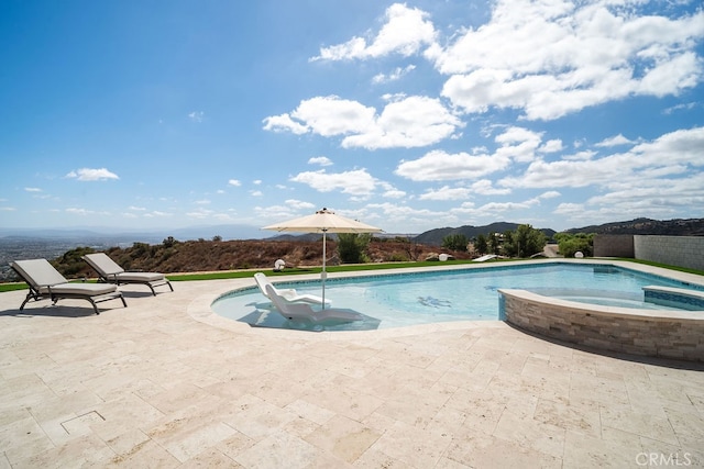 view of swimming pool featuring a patio, a mountain view, and an in ground hot tub