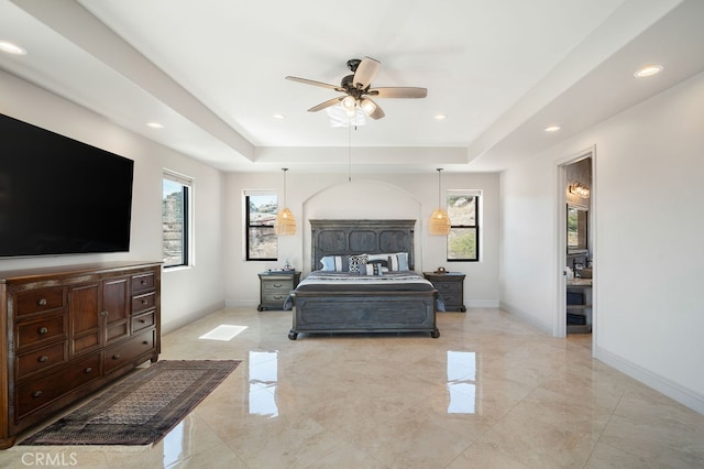 bedroom featuring multiple windows, a raised ceiling, and ceiling fan