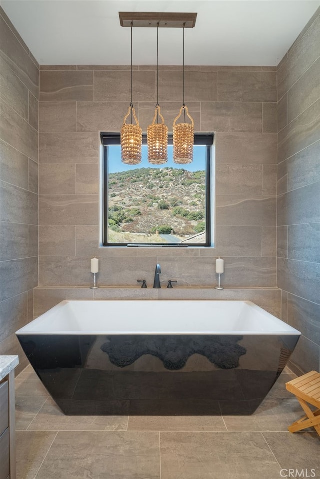 bathroom featuring vanity, a bathtub, tile walls, and a wealth of natural light