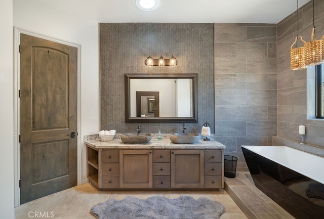 bathroom with tile walls, vanity, a tub, and tile patterned floors