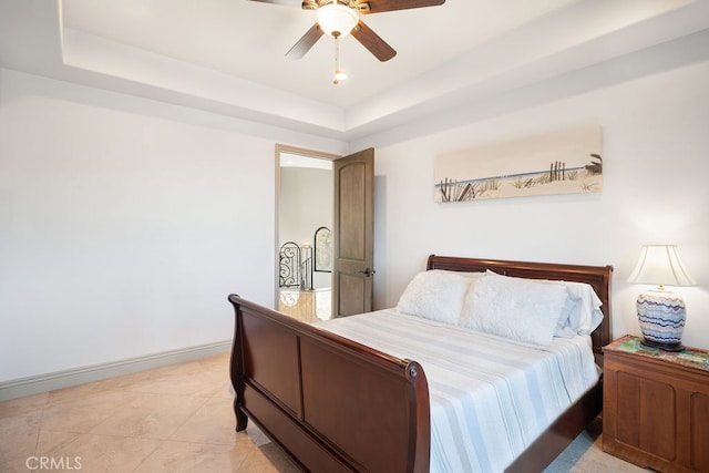 bedroom featuring a tray ceiling, ceiling fan, and light tile patterned floors