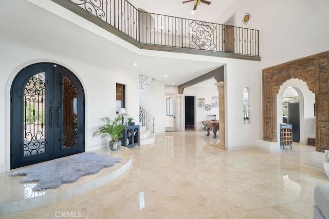 foyer entrance with a towering ceiling, ceiling fan, and french doors