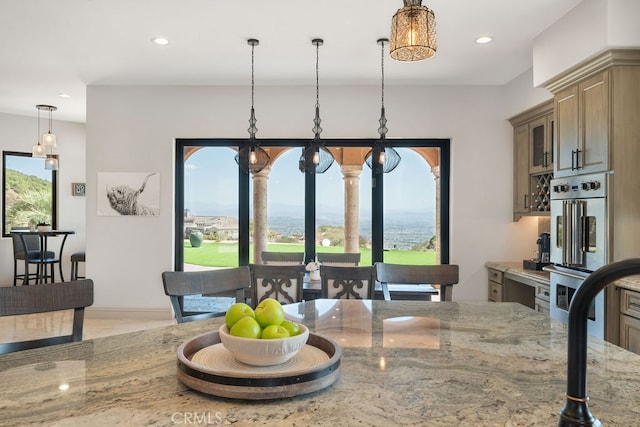 kitchen featuring light stone counters, light tile patterned floors, decorative light fixtures, double oven, and a notable chandelier