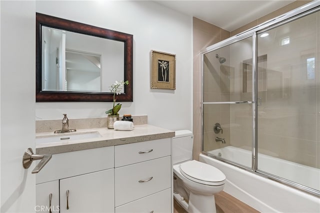 full bathroom featuring shower / bath combination with glass door, vanity, and toilet