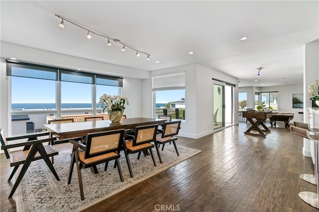 dining area with a water view, dark wood-type flooring, and plenty of natural light