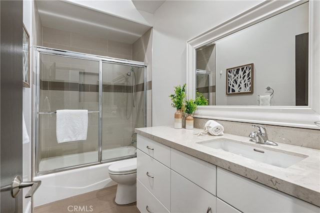 full bathroom with bath / shower combo with glass door, vanity, toilet, and tile patterned floors