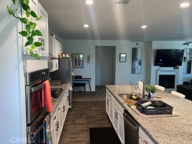 kitchen featuring white cabinetry, sink, dark wood-type flooring, and stainless steel dishwasher