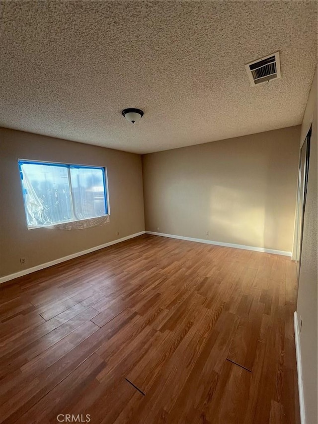 spare room with wood-type flooring and a textured ceiling