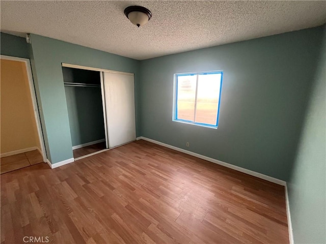 unfurnished bedroom with light hardwood / wood-style floors, a textured ceiling, and a closet