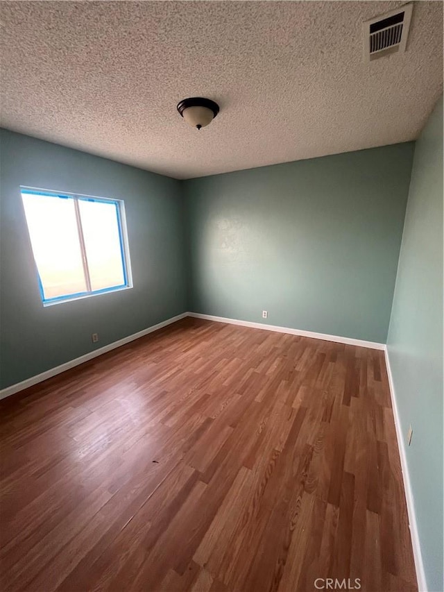 unfurnished room with wood-type flooring and a textured ceiling