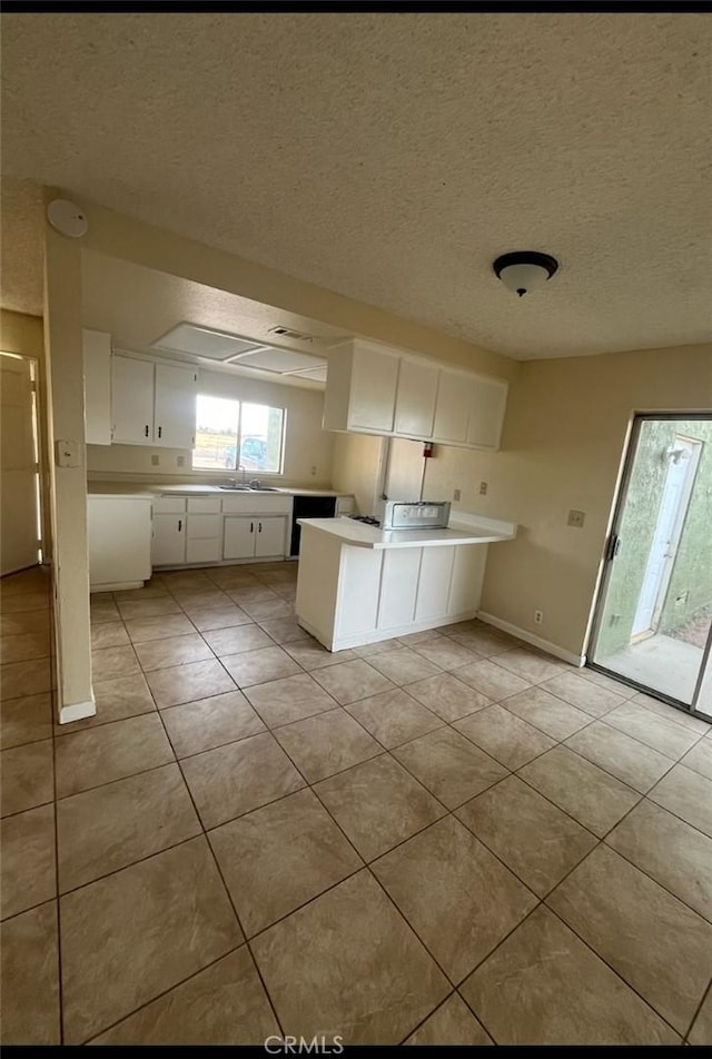 kitchen with white cabinetry, sink, kitchen peninsula, a textured ceiling, and light tile patterned flooring