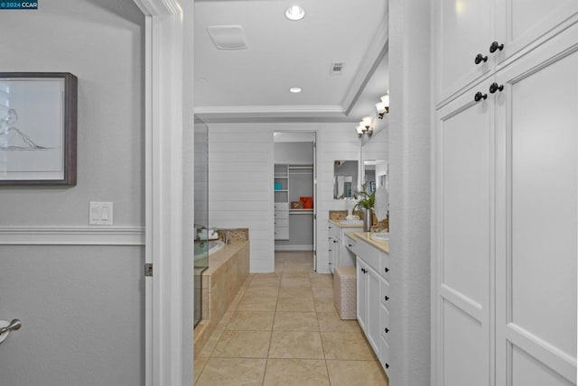 bathroom featuring vanity, a relaxing tiled tub, tile patterned floors, and crown molding