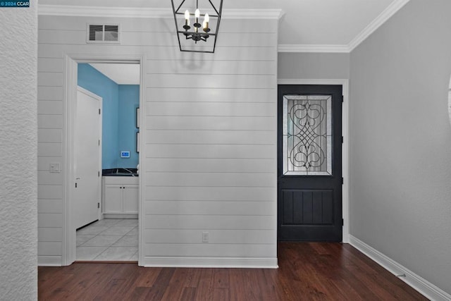 foyer entrance with a notable chandelier, dark hardwood / wood-style floors, and crown molding