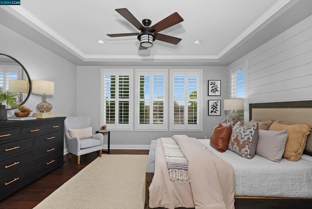 bedroom with a tray ceiling, ceiling fan, dark hardwood / wood-style flooring, and crown molding