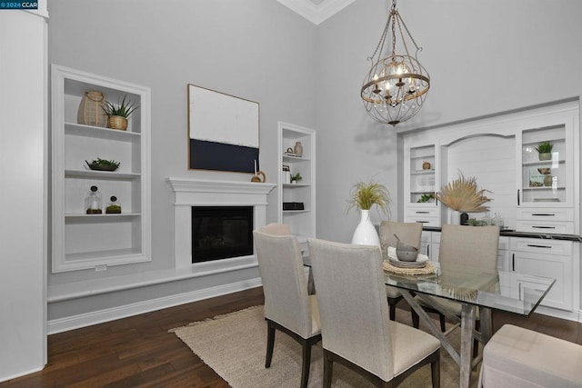 dining area featuring built in shelves, dark hardwood / wood-style flooring, crown molding, and a chandelier