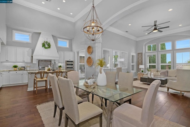 dining room with ceiling fan with notable chandelier, a towering ceiling, dark hardwood / wood-style floors, and ornamental molding