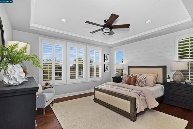 bedroom with ceiling fan, dark hardwood / wood-style floors, ornamental molding, and a tray ceiling