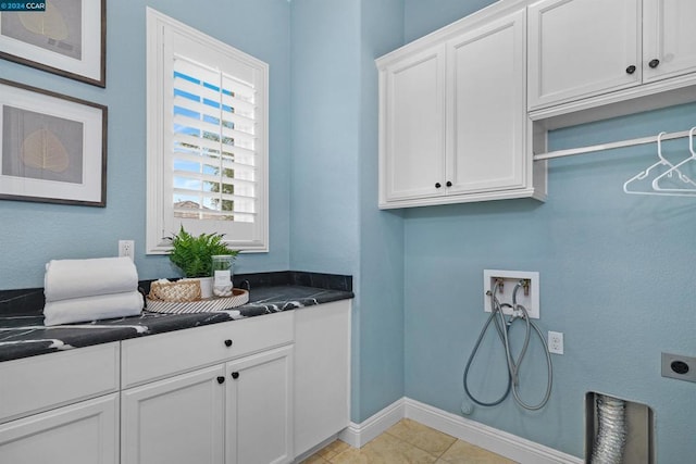 laundry room featuring hookup for an electric dryer, hookup for a washing machine, cabinets, and light tile patterned flooring