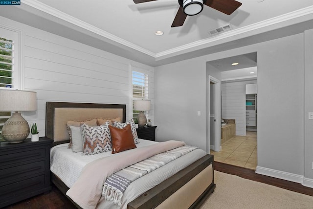 bedroom featuring ceiling fan, wood-type flooring, crown molding, and ensuite bath