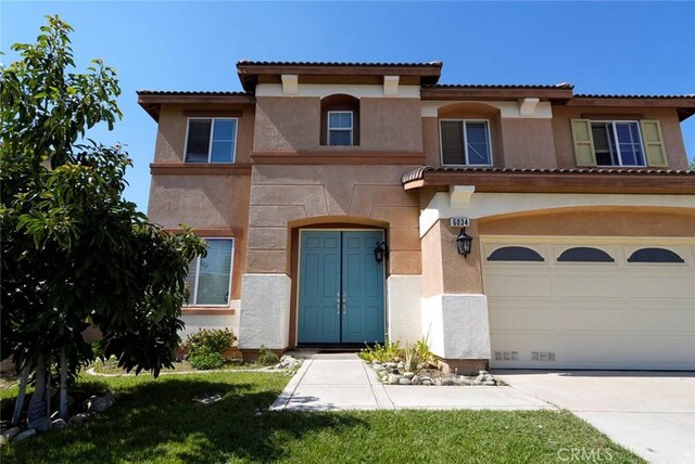 mediterranean / spanish home featuring a garage and a front lawn