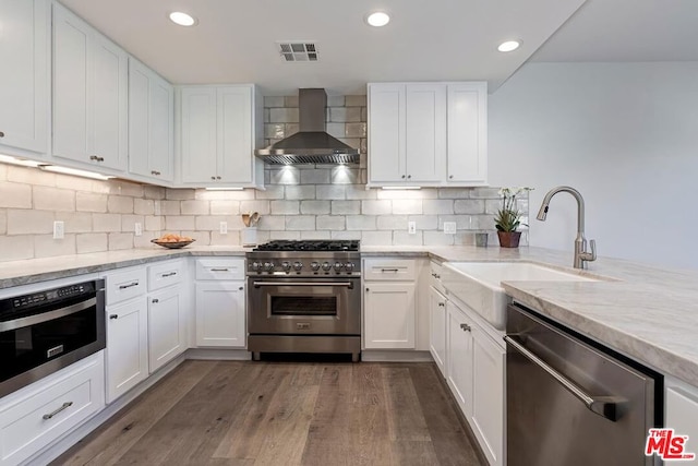 kitchen with stainless steel appliances, white cabinetry, dark wood-type flooring, and wall chimney range hood